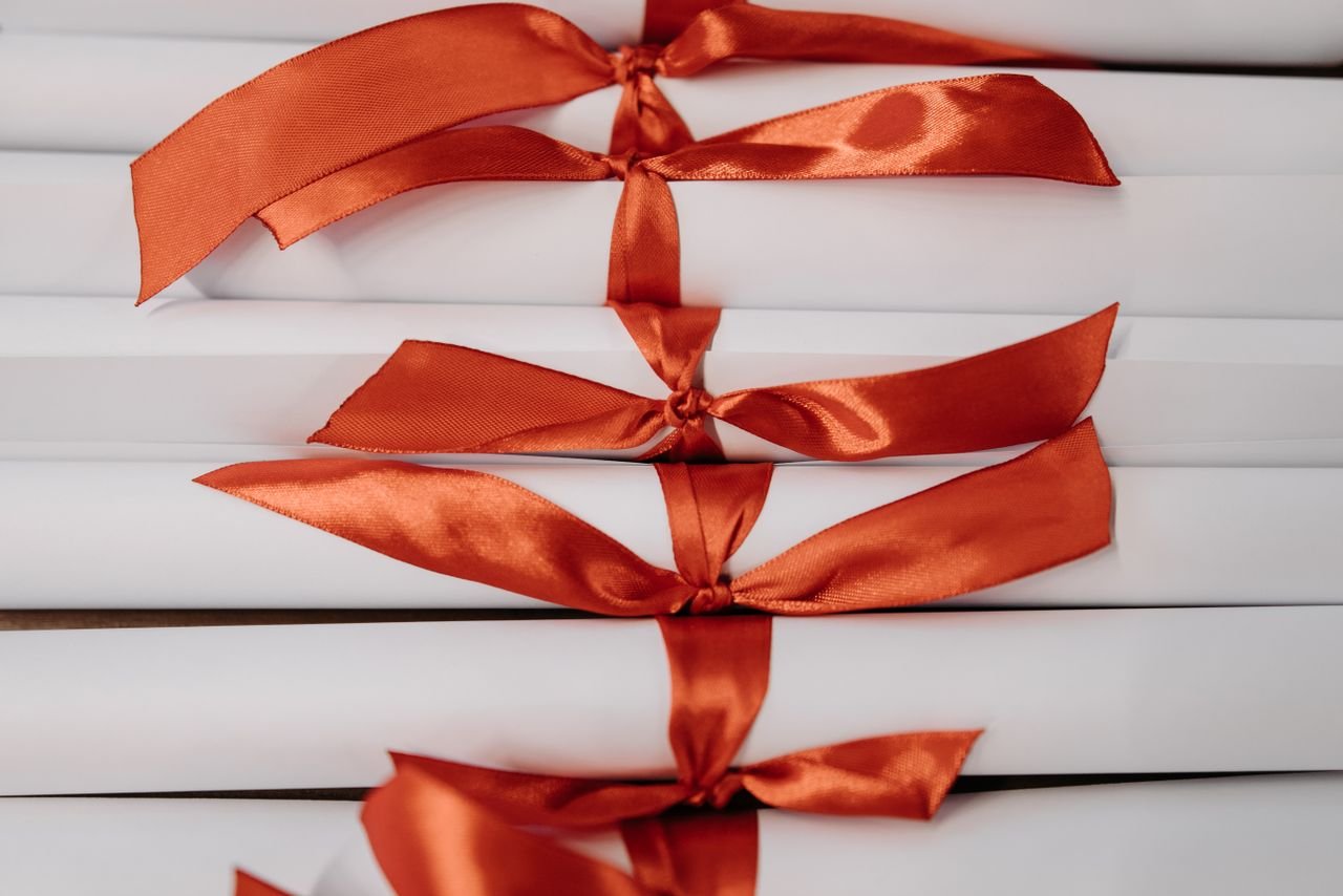 Close-up of graduation diplomas tied with vibrant red ribbons, symbolizing achievement and success.